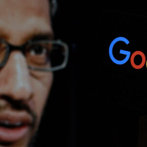 In this photo the Google logo is displayed on the smartphone screen with CEO Sundar Pichai in the background.
