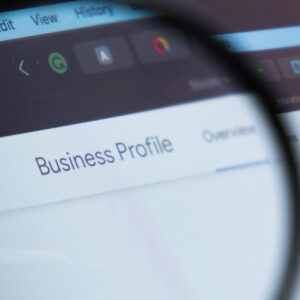 Google Business Profile logo on the screen of laptop through magnifying glass,