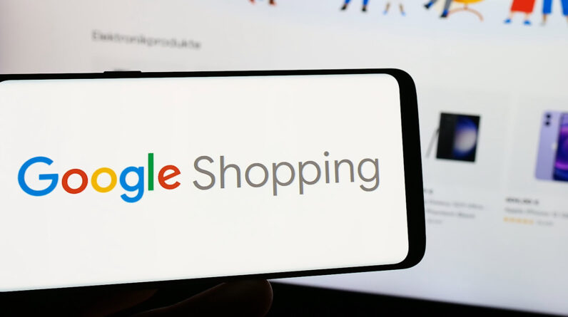 Person holding smartphone with logo of product search platform Google Shopping on screen in front of website.